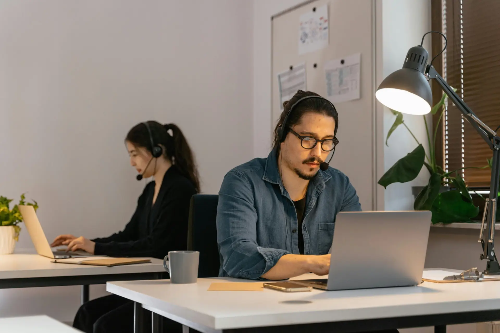 Two call center employees working diligently with headsets in the office.